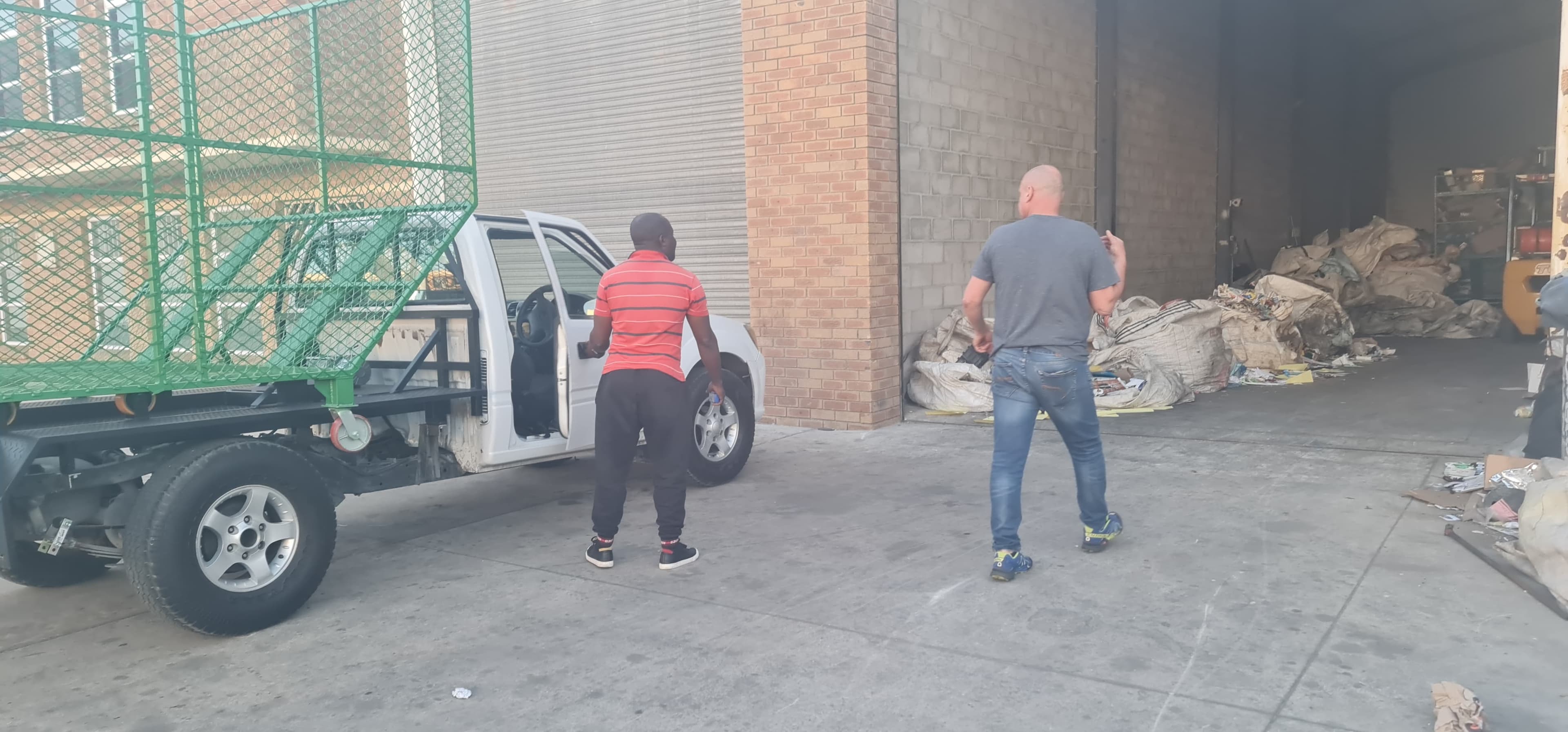 A bakkie with a cage at the warehouse roller door where loose recyclables are received for sorting