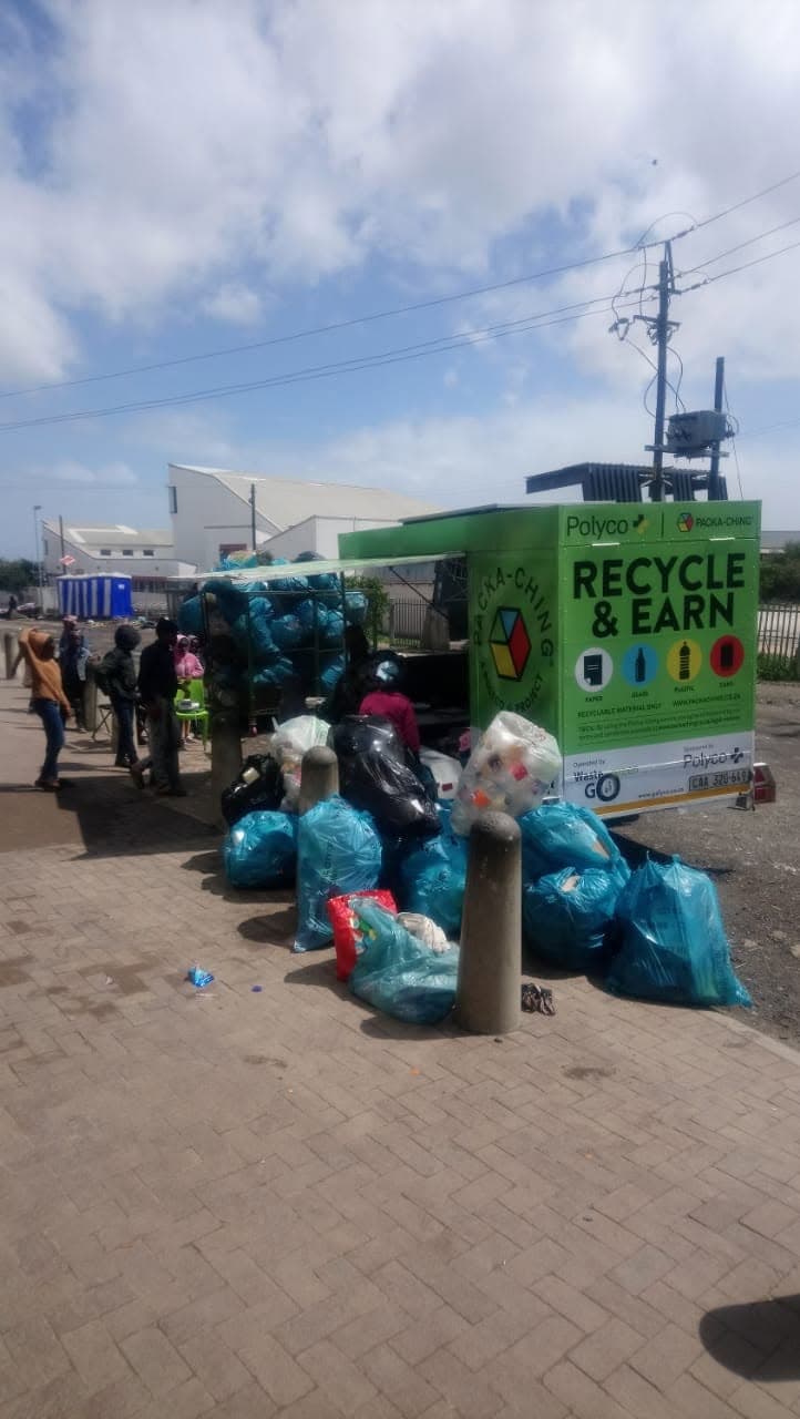 Community members bringing bags of recyclables to a green Packa-Ching ‘Recycle & Earn’ mobile buyback unit operated by WasteGo Green in partnership with Polyco