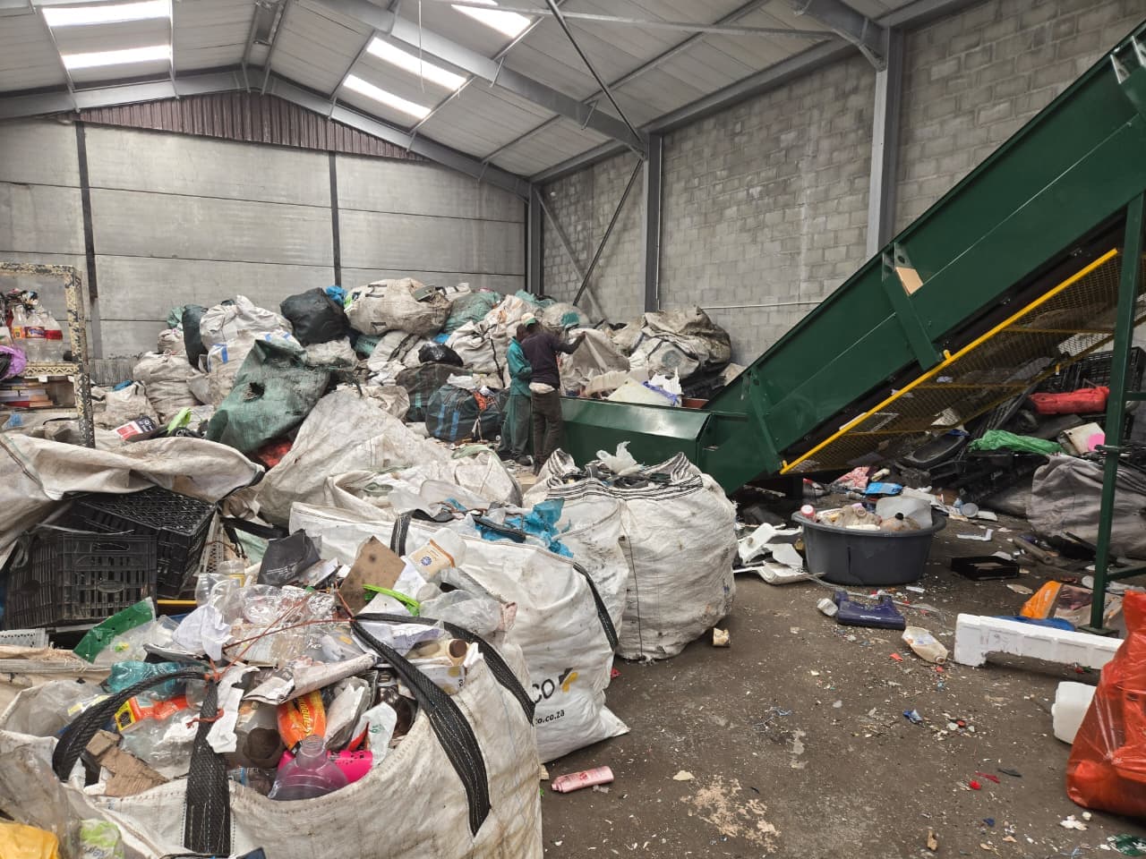Bulk bags of sorted recyclables stacked beside a conveyor in the WasteGo Green warehouse ready for baling